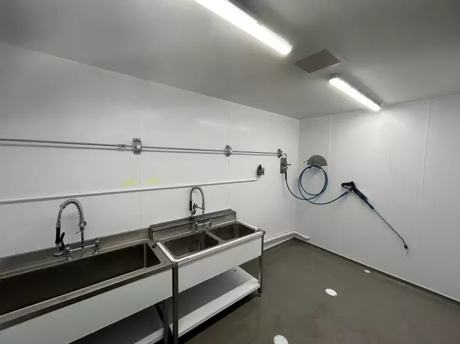 Stainless steel washroom with installed pipework, hose point and trigger gun connected to the wall-mounted pressure washer system in Nottingham